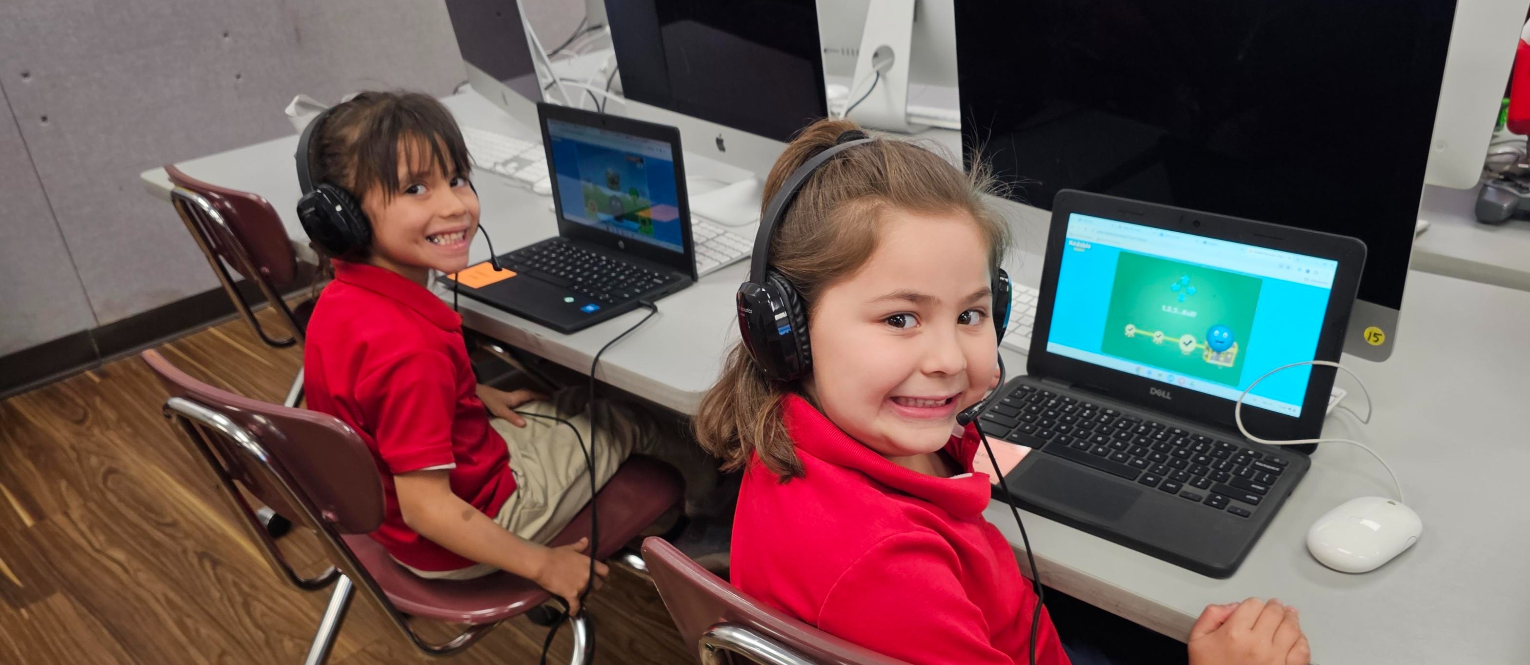 Students smile for the camera while coding