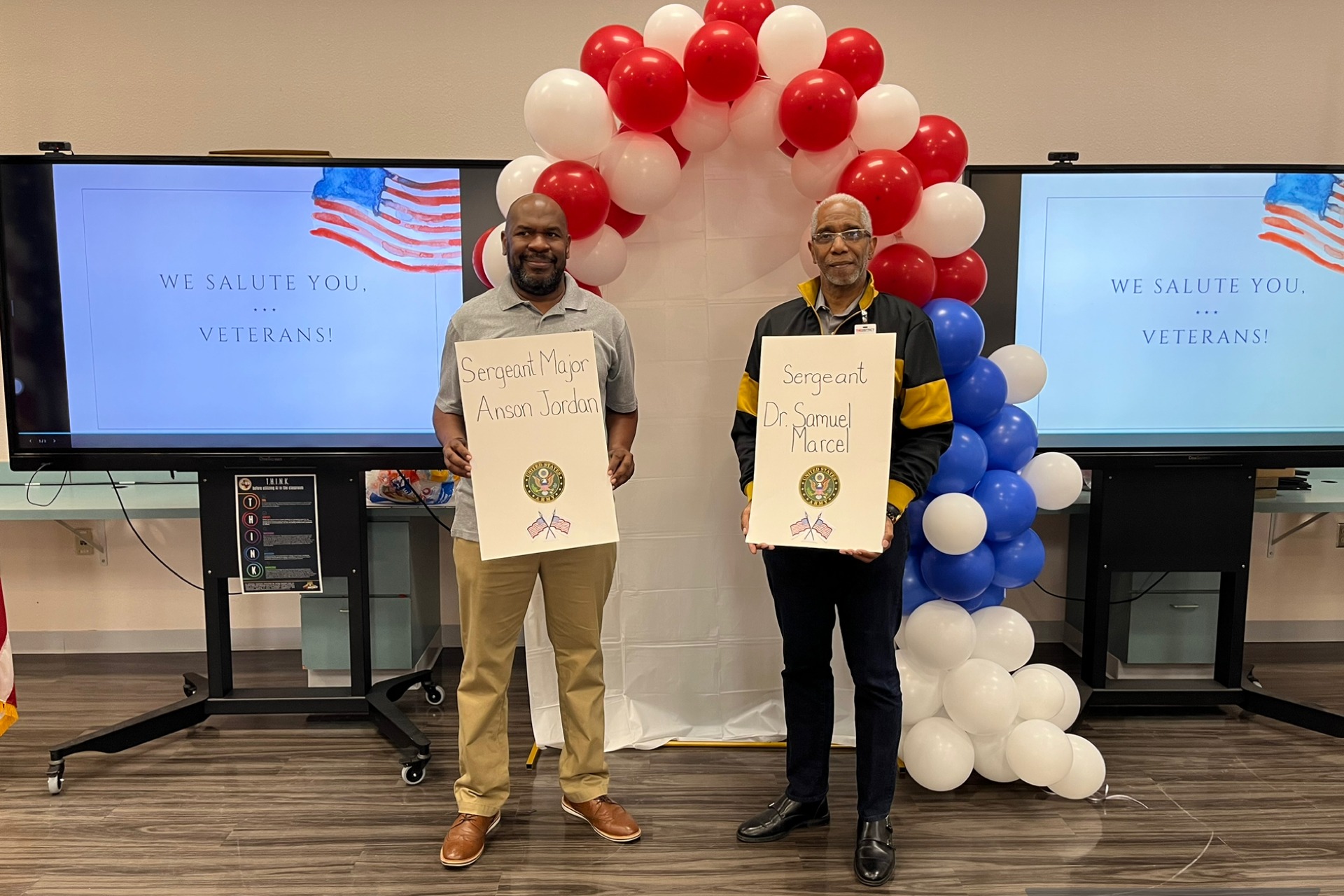 Members of Theta Delta Lambda Chapter of Alpha Phi Alpha Fraternity holding their poster during the Veteran's Day parade celebration 