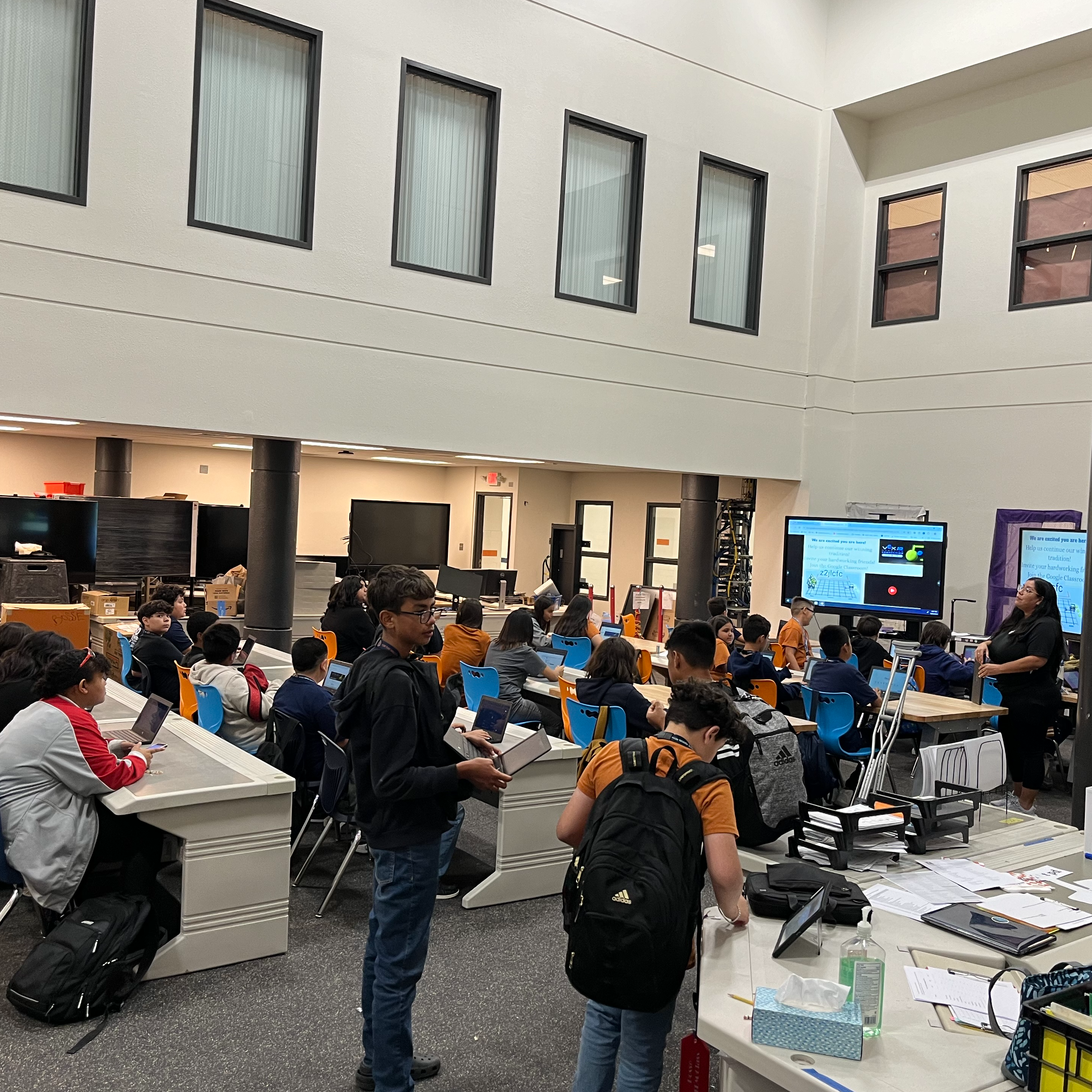 Robotics team meeting with students sitting in rows listening to the STEM teacher for directions