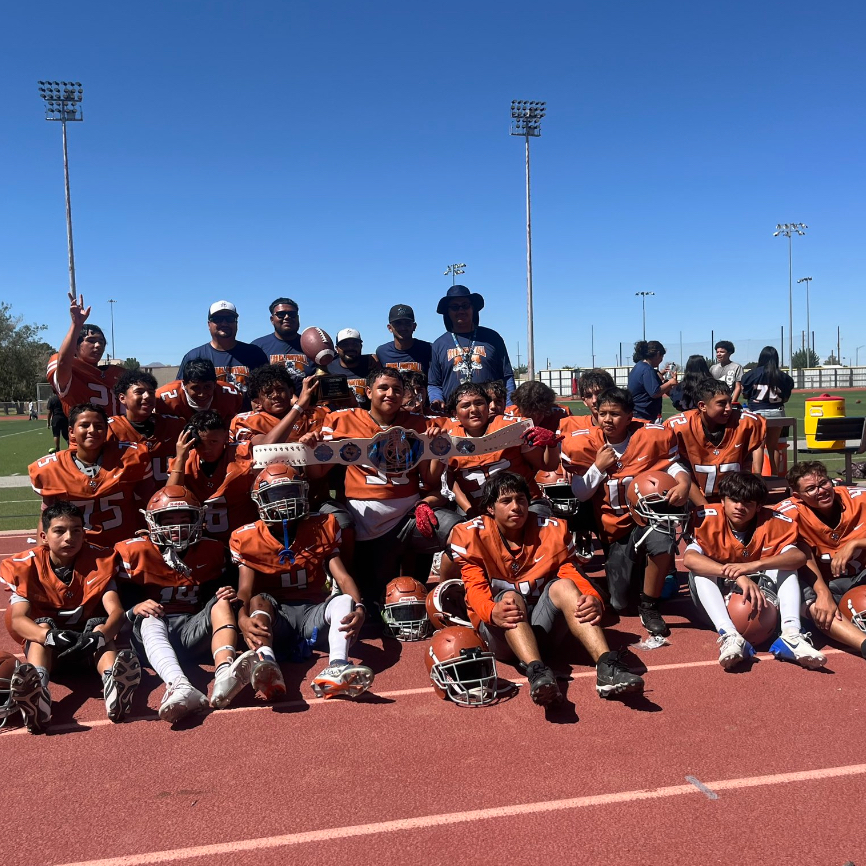 8th grade football team with their coaches posing for a team picture holding the district trophy after going undefeated the whole season