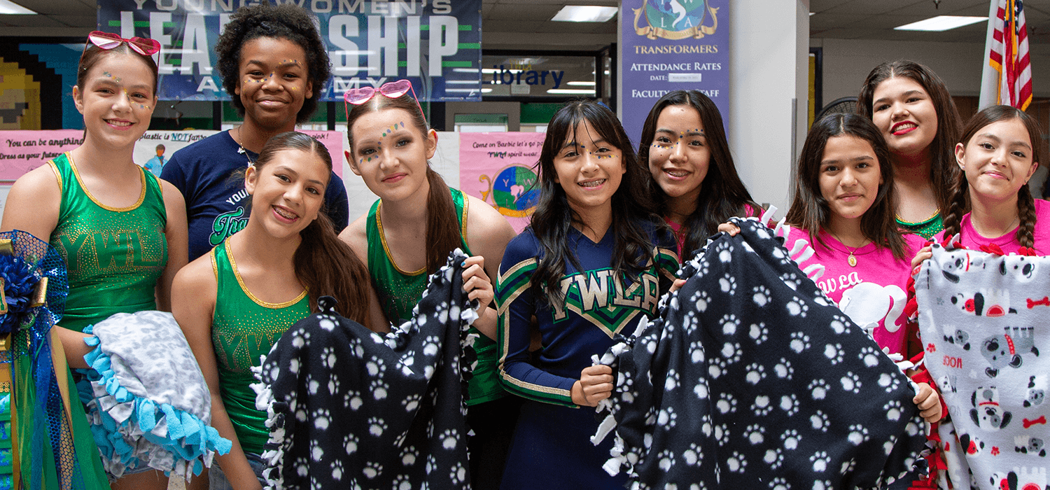 girls holding up blankets they made for the community