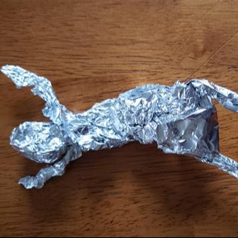 Shiny silver item resting on a wooden surface, creating a contrast in textures.