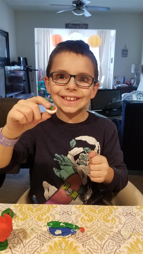 A smiling boy wearing glasses and a blue shirt.