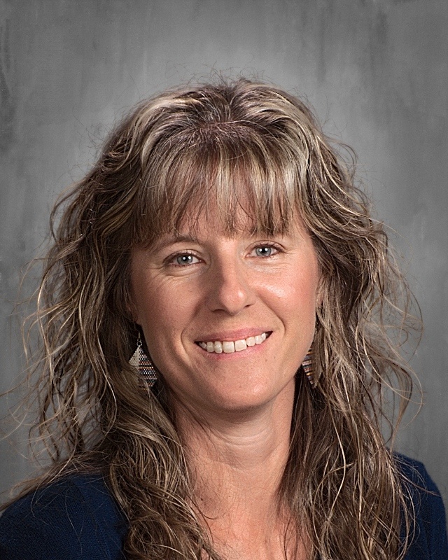 A lady with a long blonde curly hair smiling.