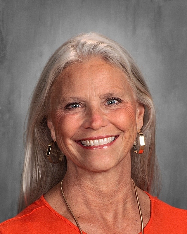 A lady with white hair wearing orange shirt.
