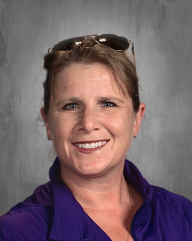 A lady wearing blue polo shirt with sun glasses on top of her head.