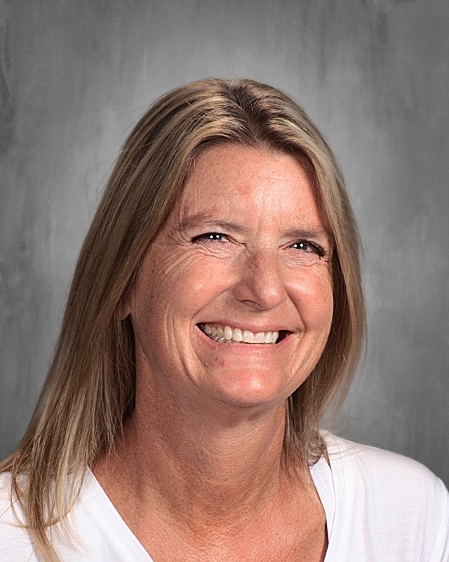 A lady with blonde hair wearing white shirt smiling for a picture.