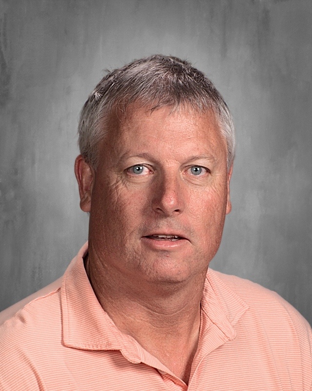 A guy with white hair wearing pink polo shirt.