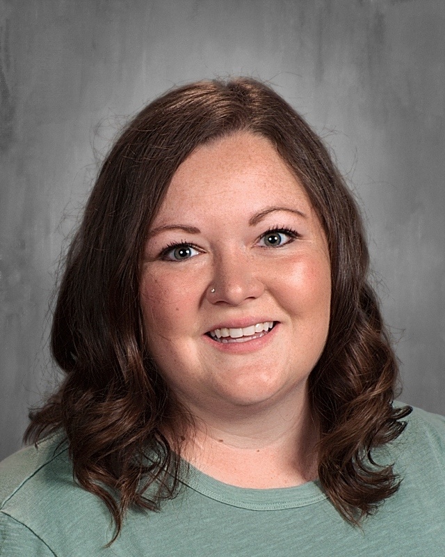 A lady with curly black hair wearing gray shirt.