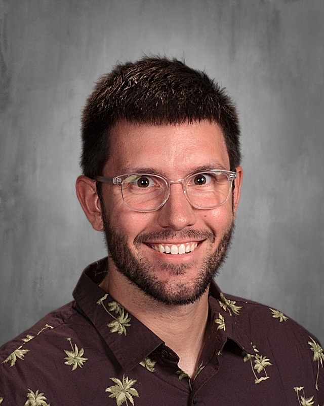 A guy wearing eye glasses and a floral polo.