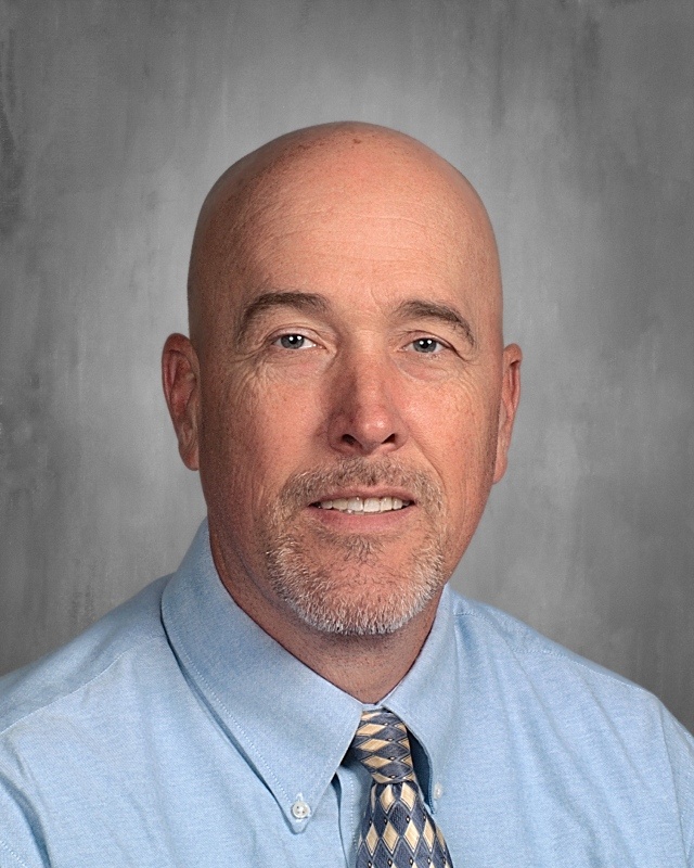A bald guy wearing blue long sleeves with tie.
