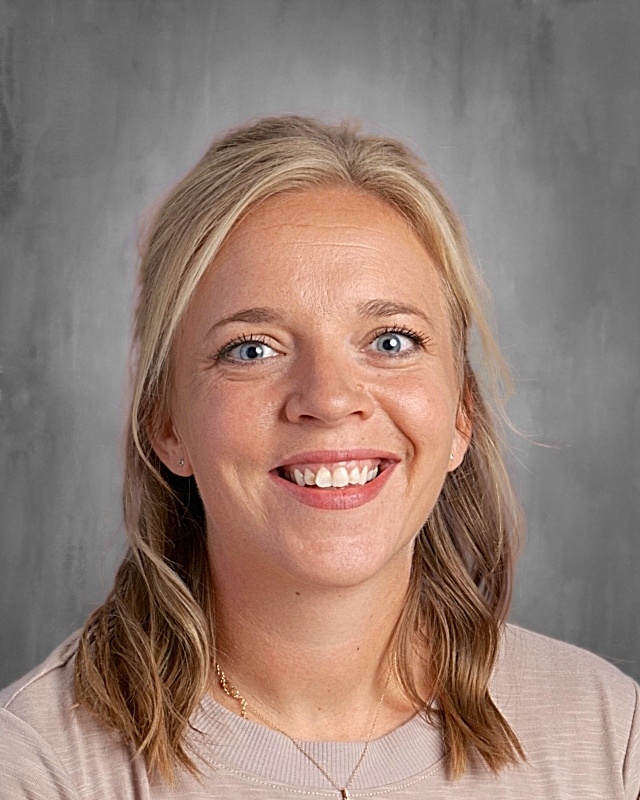 Lady with blonde hear wearing a tan shirt. 
