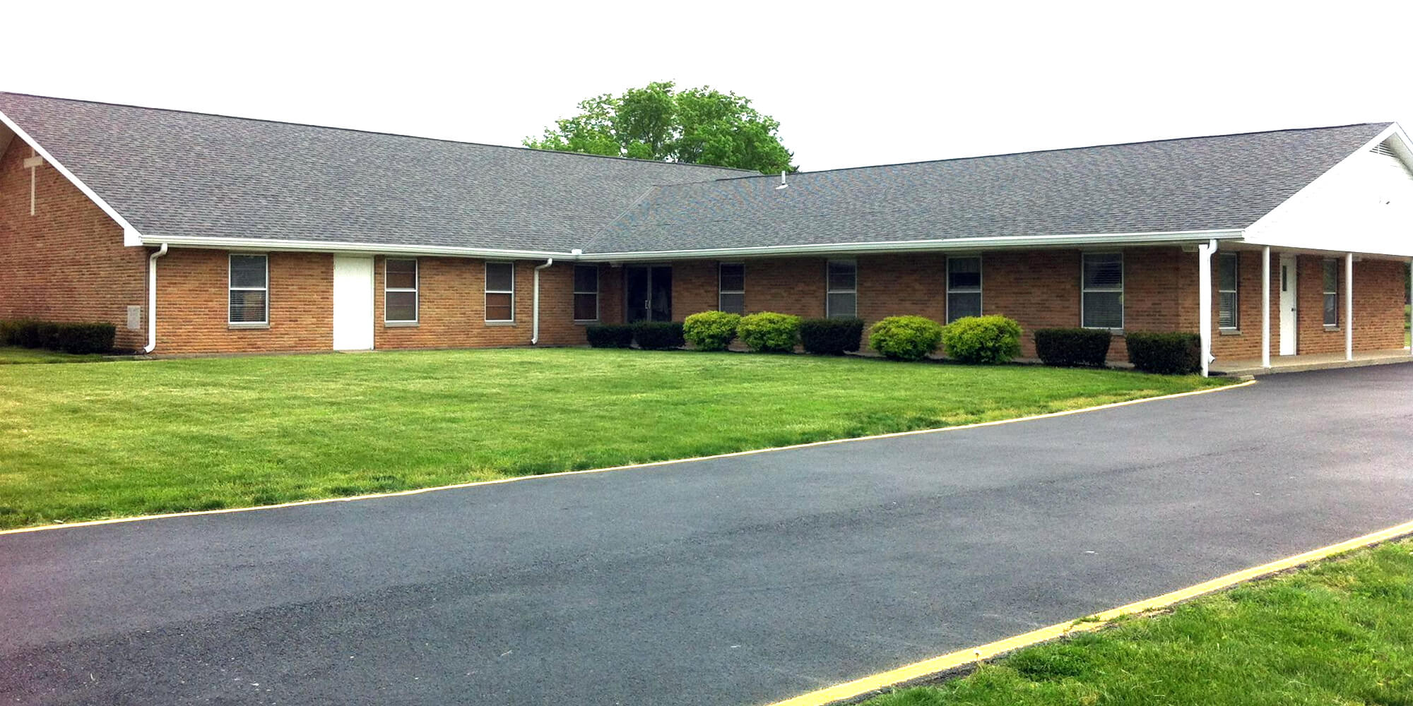 Brick building with driveway and grass in front.