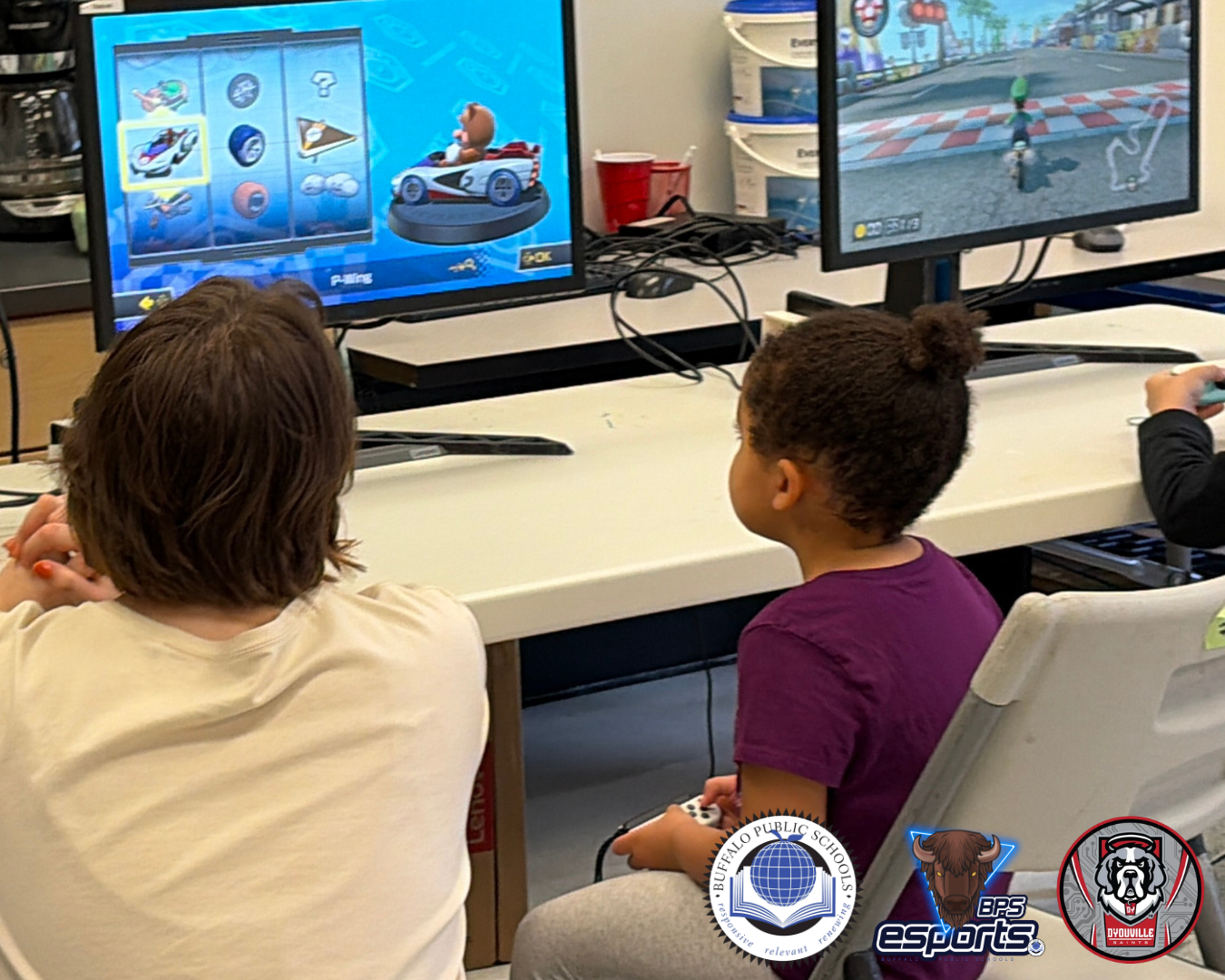 Una niña pequeña es ayudada por una mujer adulta que juega a un videojuego en un ordenador.