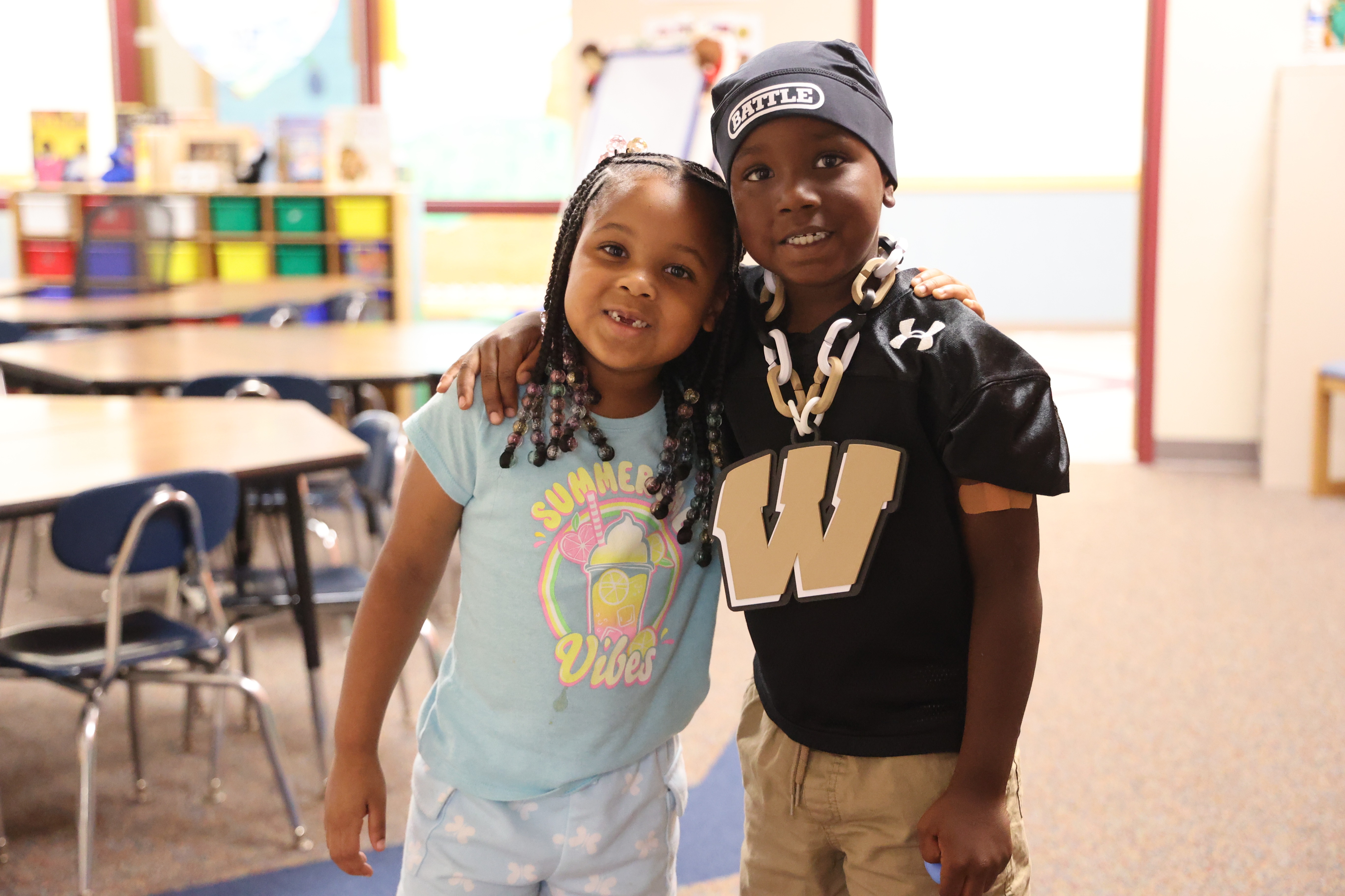 Little girl and boy wrapping their arms around each other and smiling