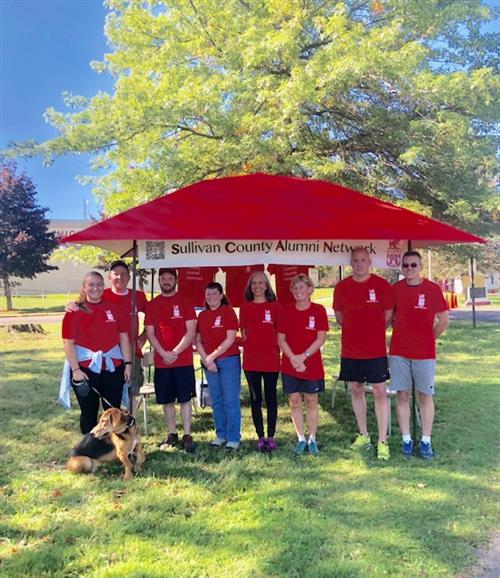 A group of people standing under a red tent