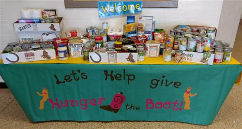 A table with a sign and various kinds of food at the top