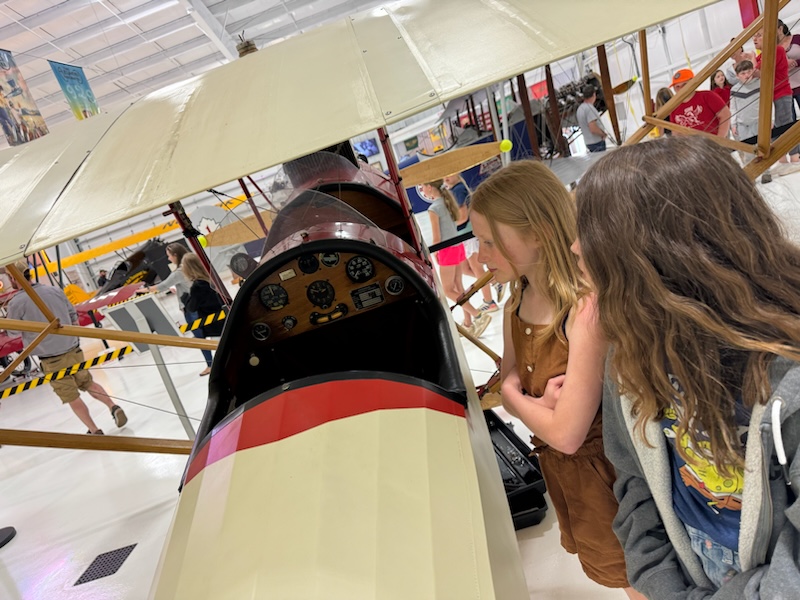 two students looking at a small airplane in a museum