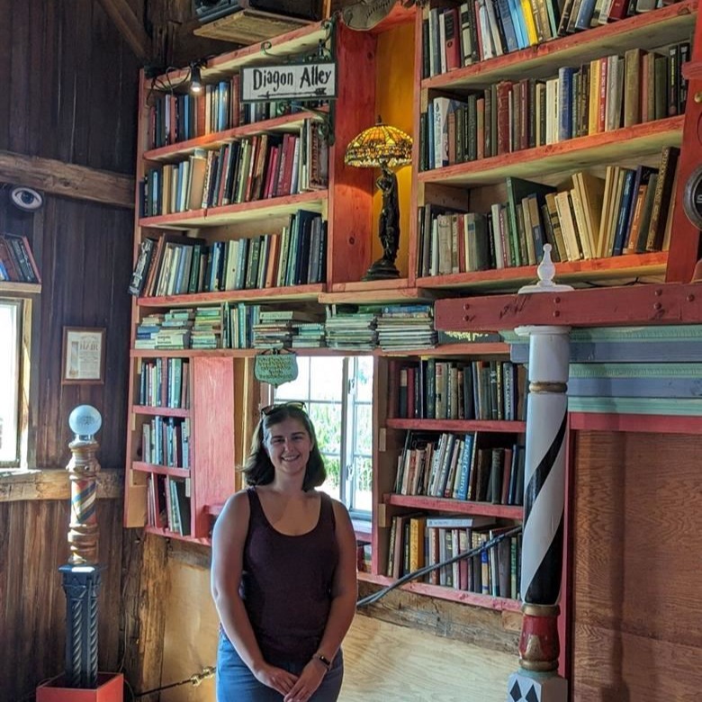 Mrs. Kinsey standing in front of an antique bookshelf
