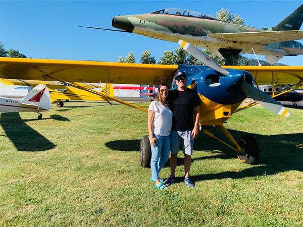 2 persons smiling standing in front of a helicopter