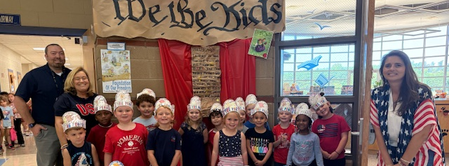 students sitting under we the kids banner
