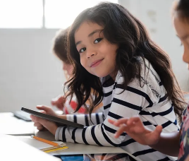 student in the classroom with her ipad smiling