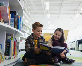 students in the library sitting and reading a book