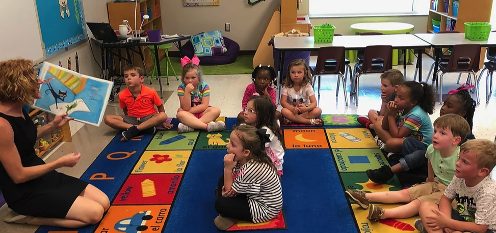 teacher reading a book  to the students in the classroom 