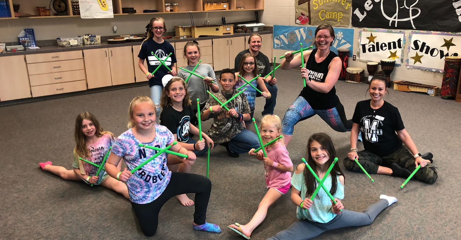 students and teachers flexing legs and holding sticks