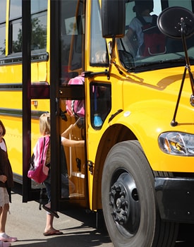 Elementary students get on a school bus