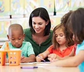 teacher next to little students doing an activity together