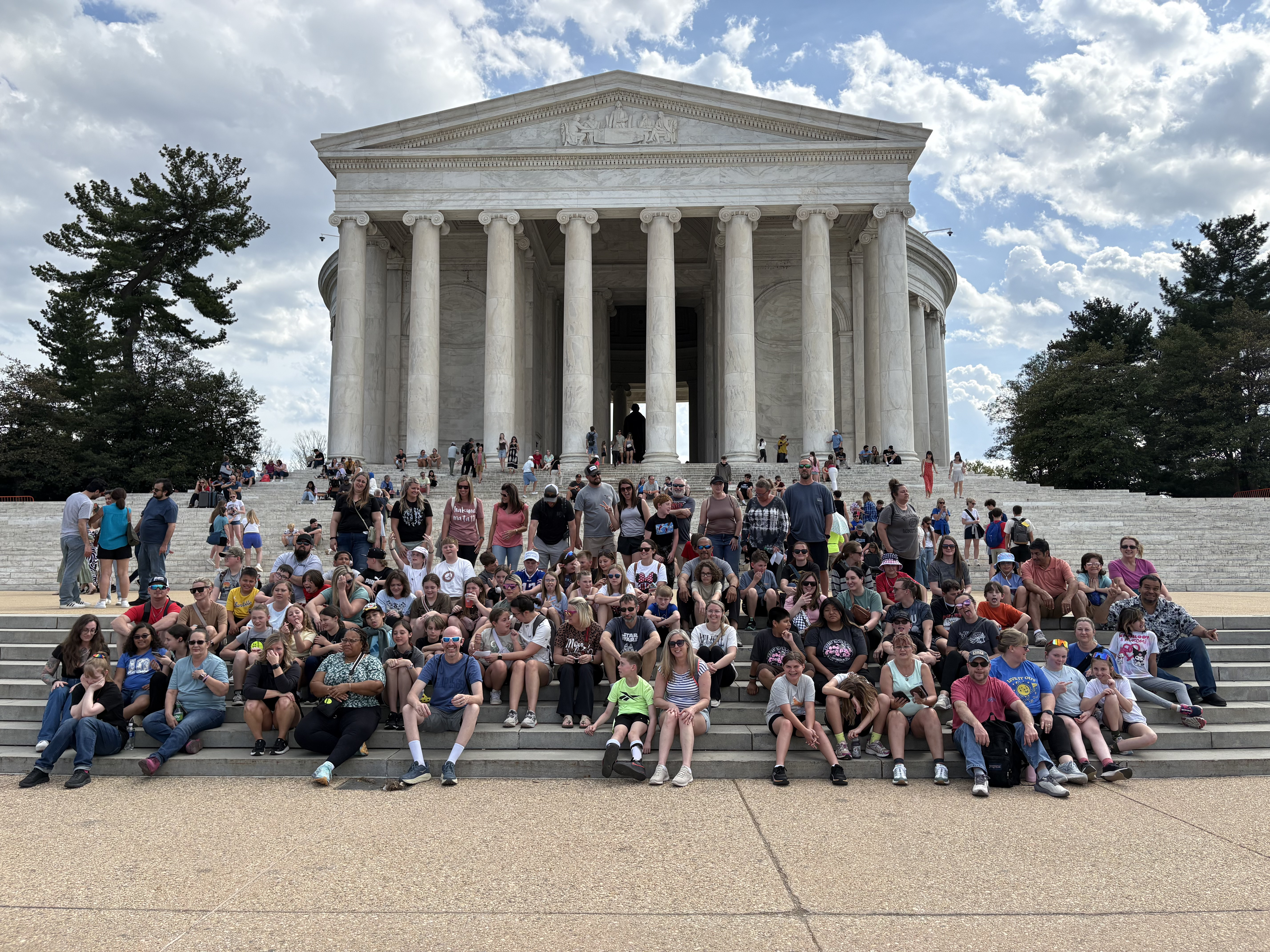 Students and families seated in front of the Jefferson memorial in Washington DC