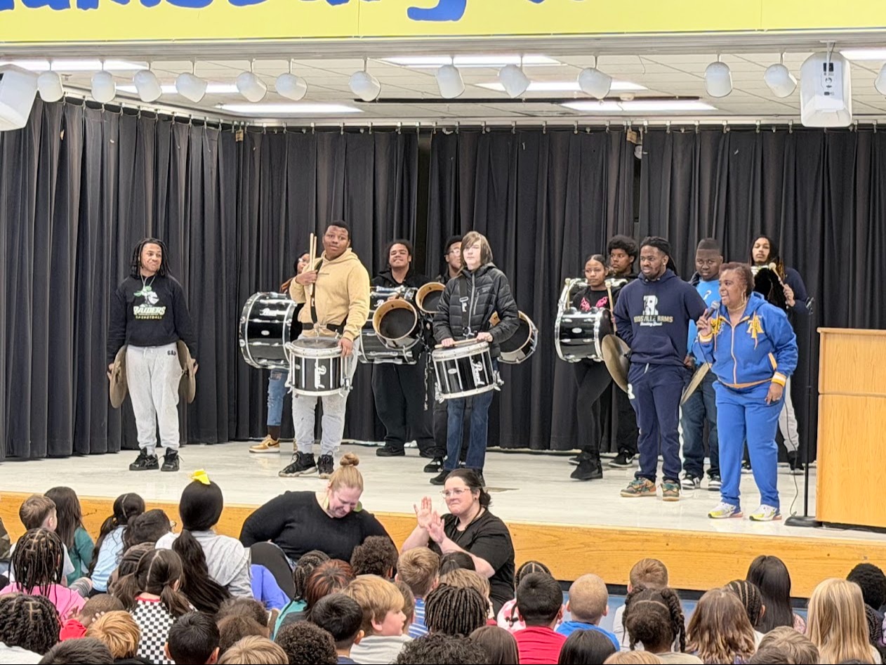 During the Black History Month program, the high school marching band performs on the school stage.