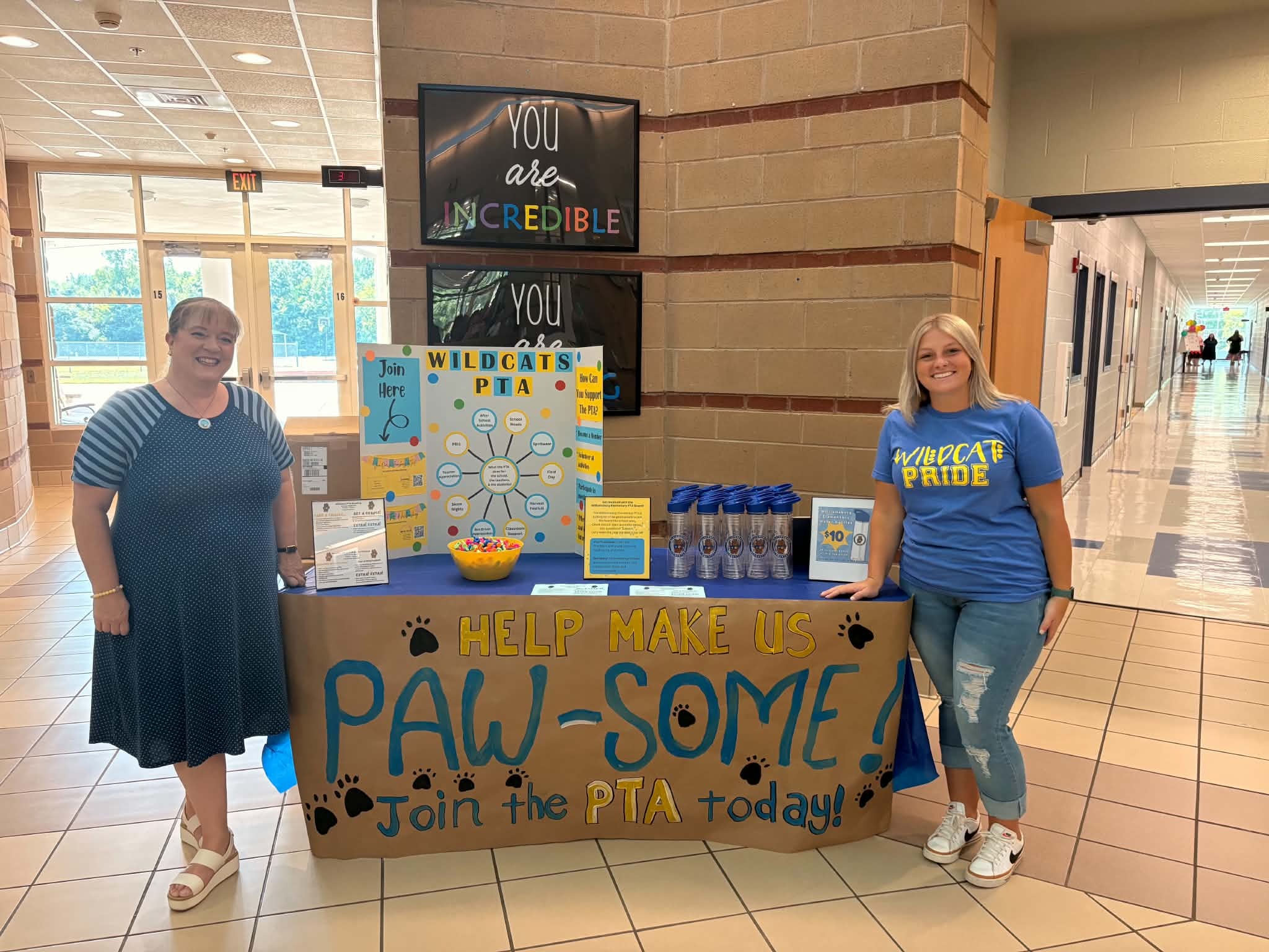 Parent Teacher Association board leaders standing by the table to promote the PTA at the beginning of year open house event.