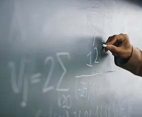 Teacher Writing a Formula on a Blackboar