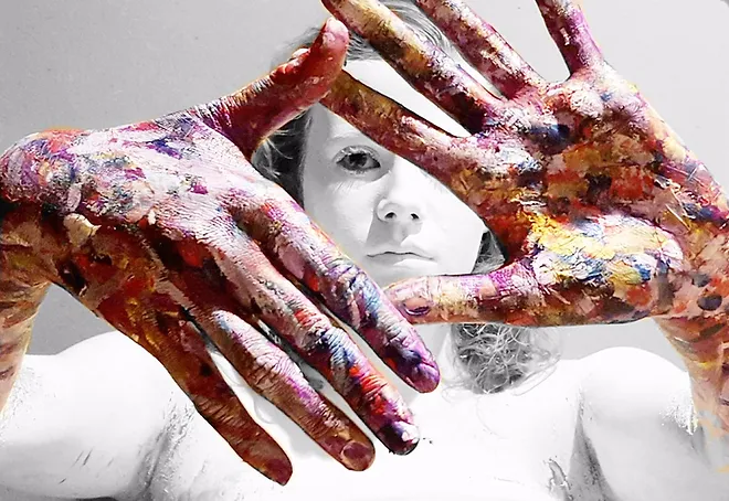 student in black and white, showing her hands covered in paint