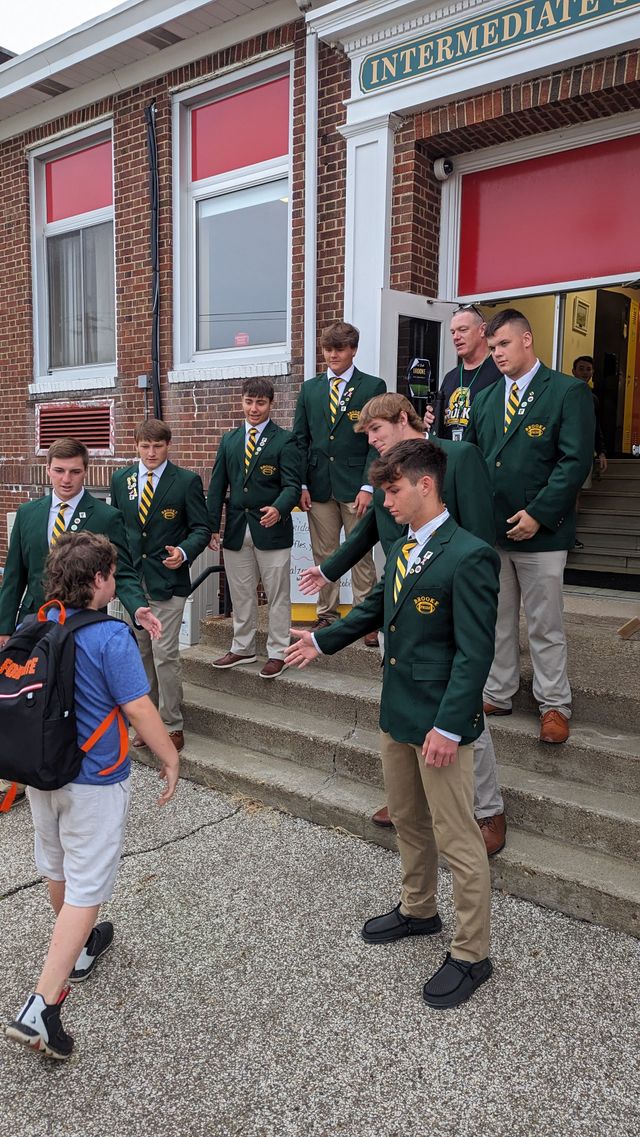 Group of students wants to shake hands with another student.