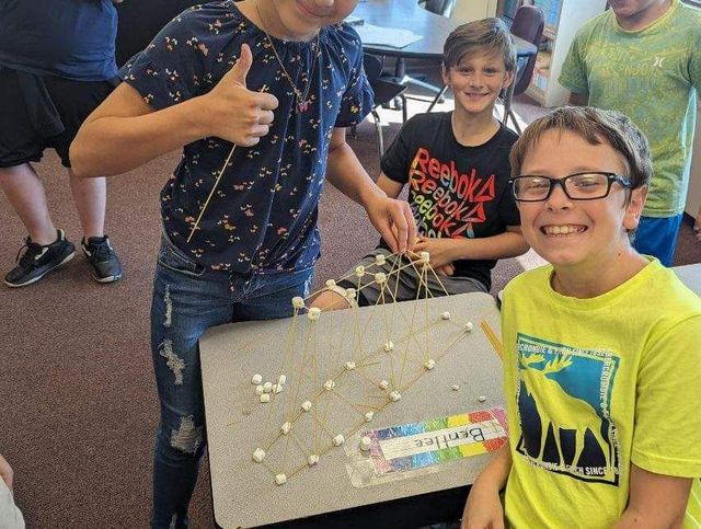 Students posing for a picture while building a miniature.