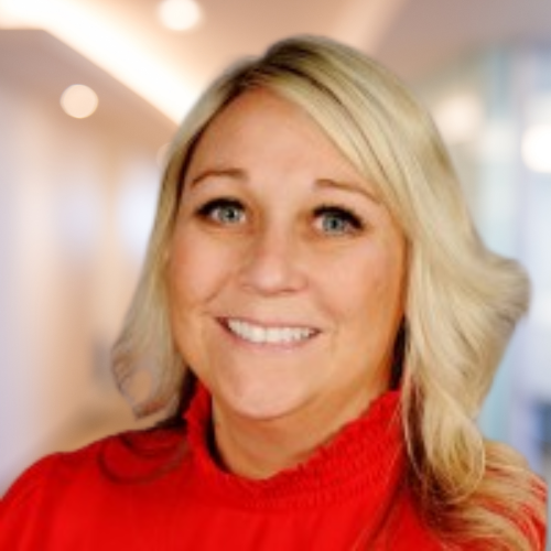 Woman blond hair blue eyes smiling wearing red shirt with office background