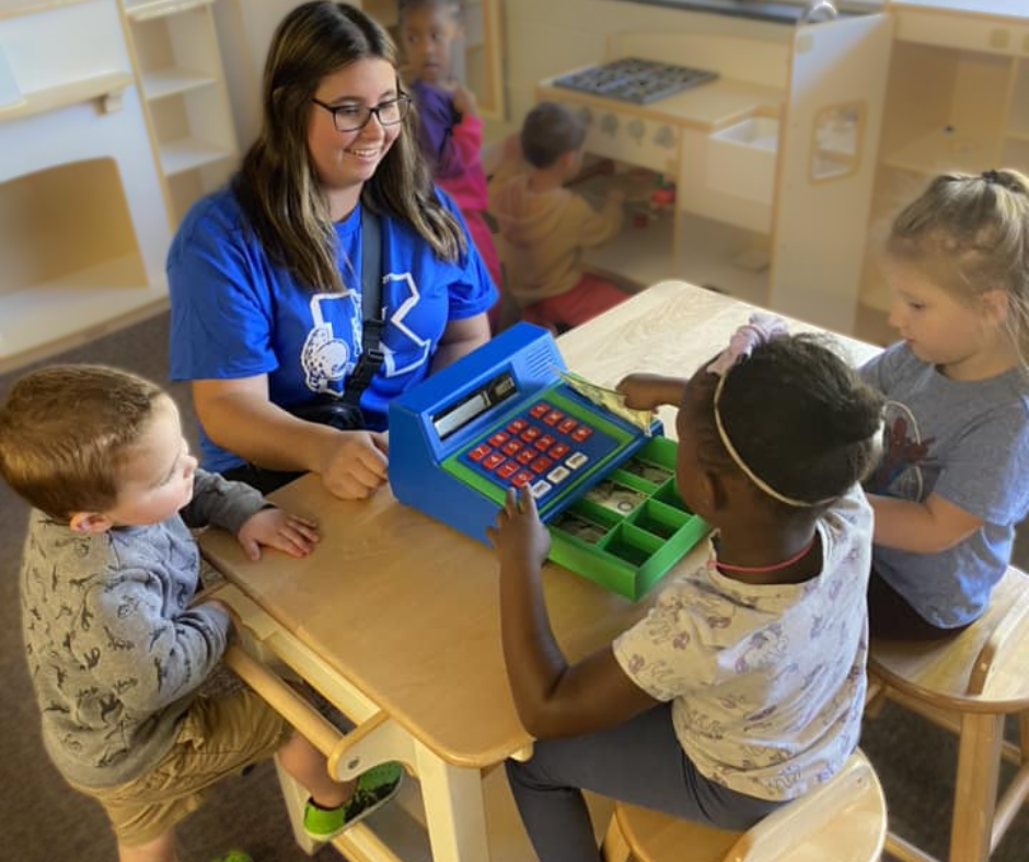 High School student visiting preschool and playing store with young students