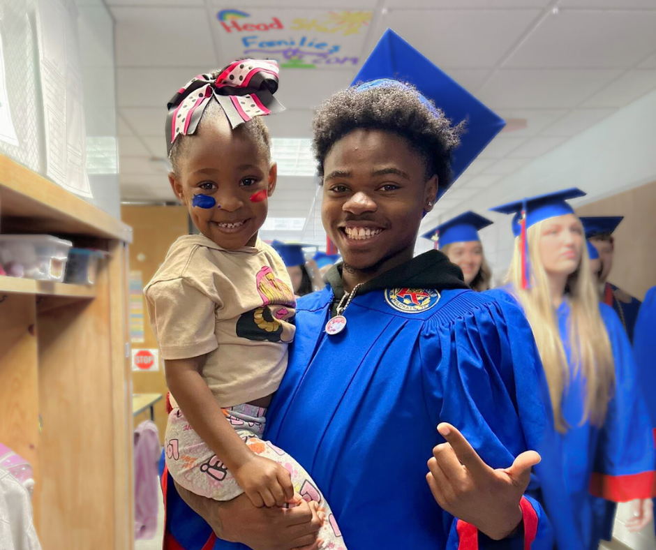 High School senior in blue graduation cap and gown visiting his preschool age sister