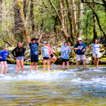 happy students standing in water cleaning creek