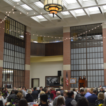 people gathered in large auditorium with hanging lights