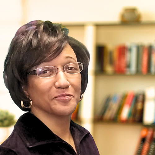 woman wearing glasses in front of bookshelf