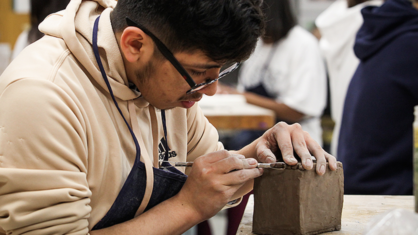 High school student working to create a clay sculpture.