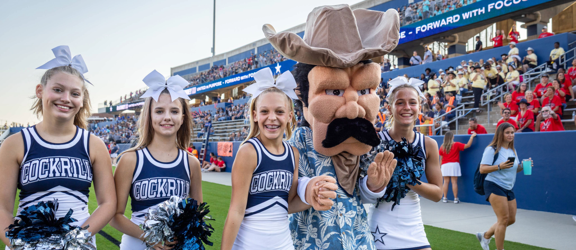 Four Cheerleaders from Cockrill Middle School walk with the cowboy mascot