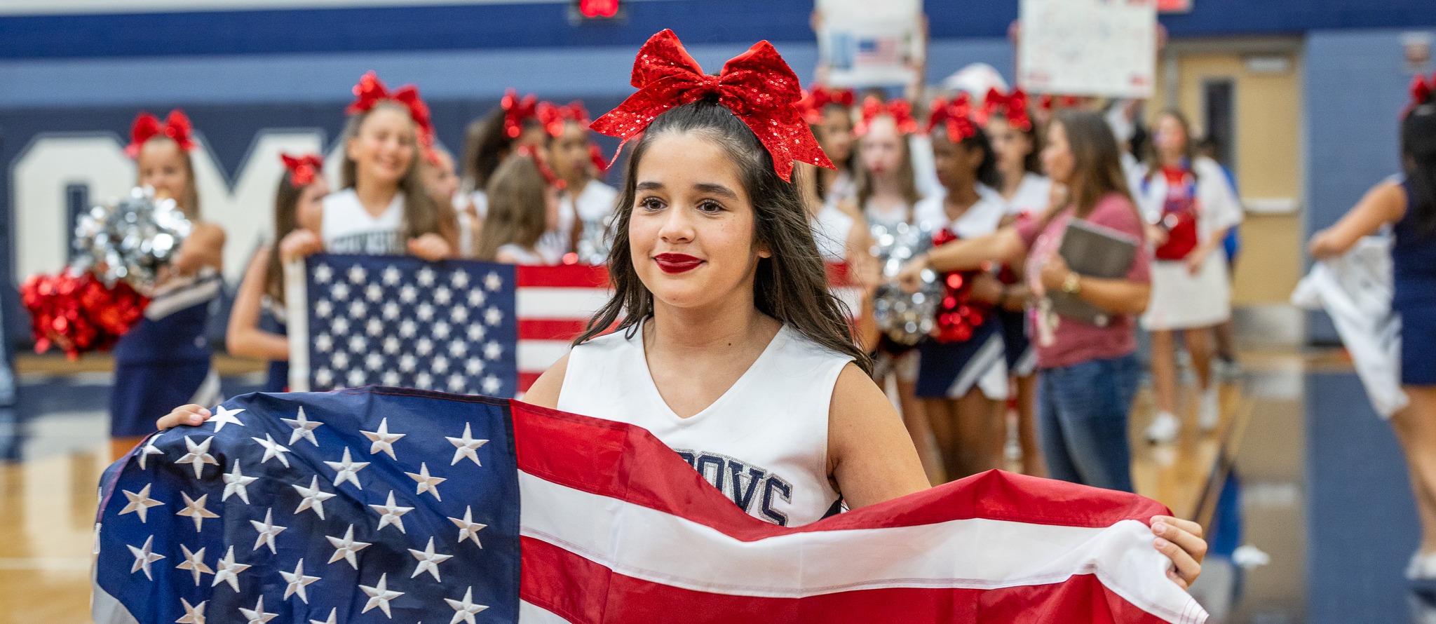 a cockrill middle school cheerleader carries a flag during the patriot day parade