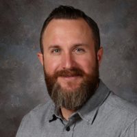 A man with a beard wearing a gray shirt.