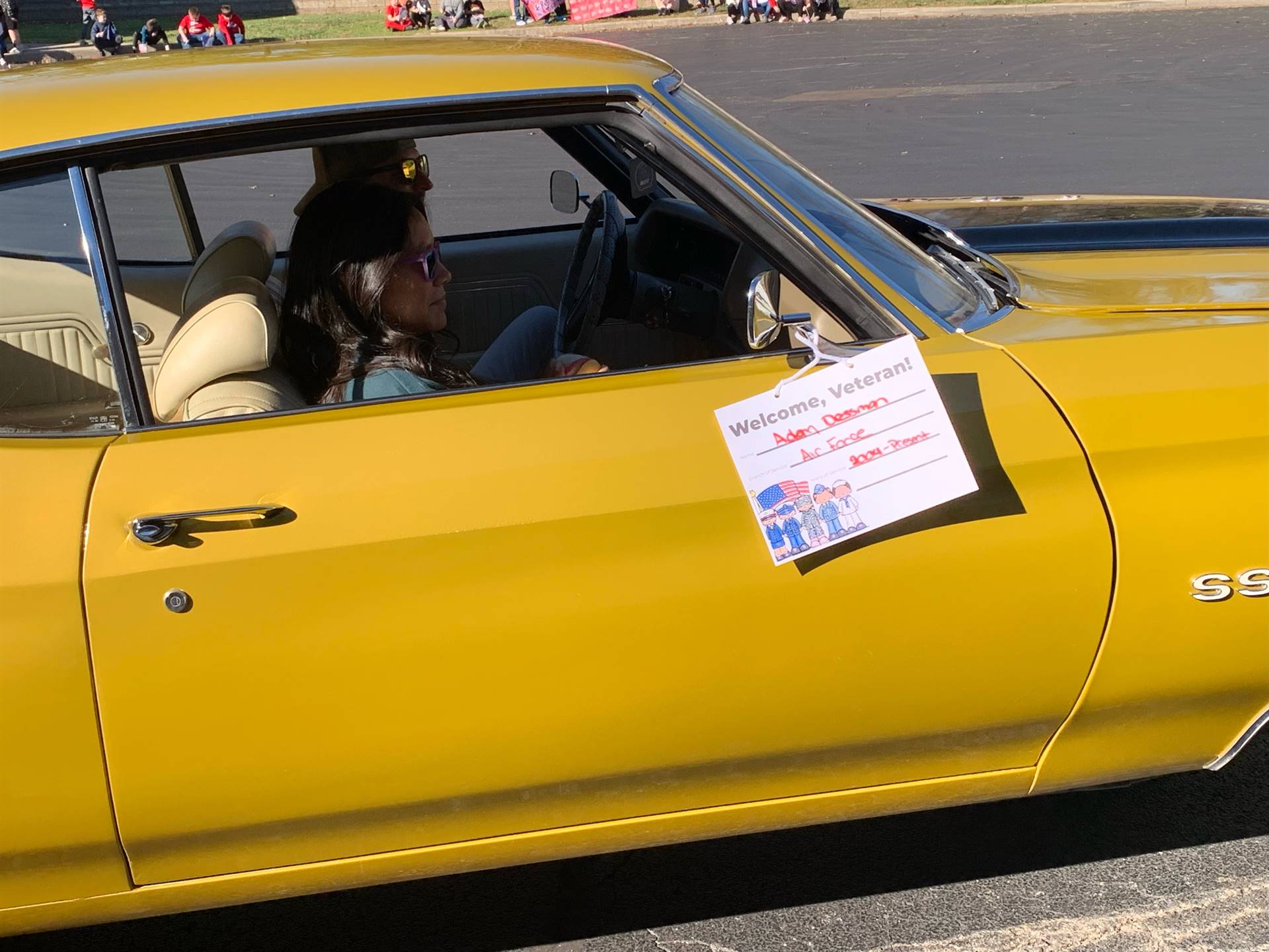 A woman driving a yellow muscle car.