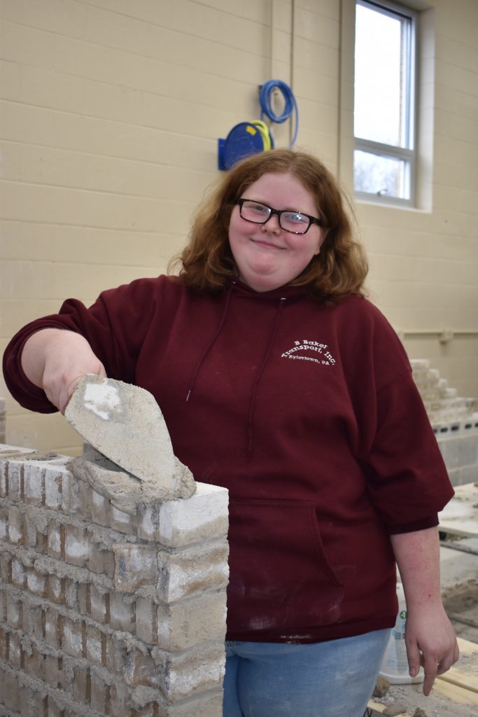 A photo of a woman putting cements on bricks